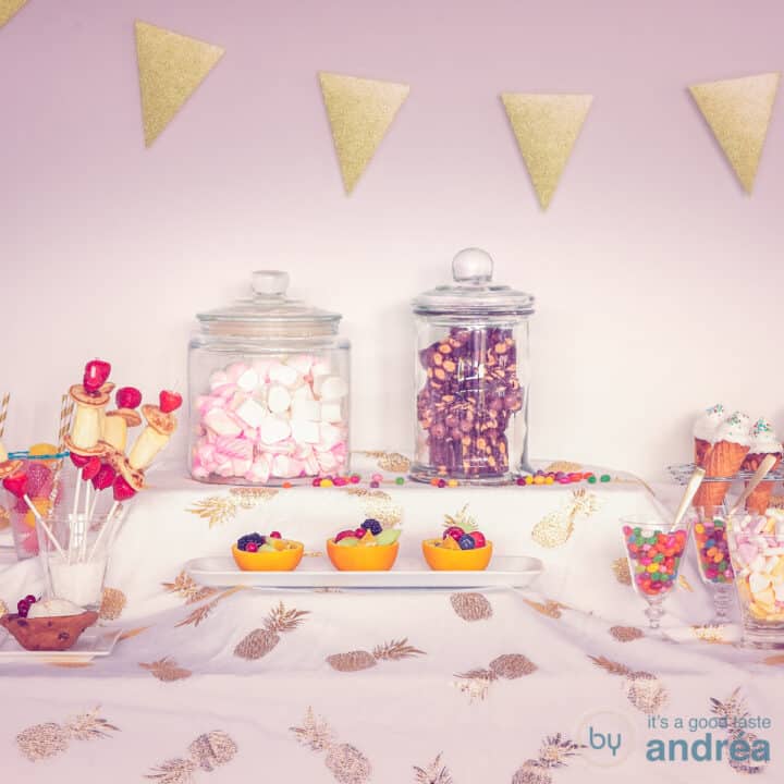 Een vierkante foto van een sweet table die gemaakt kan worden voor een kinderfeestje, met baksels en snoepjes, fruit en drinken.