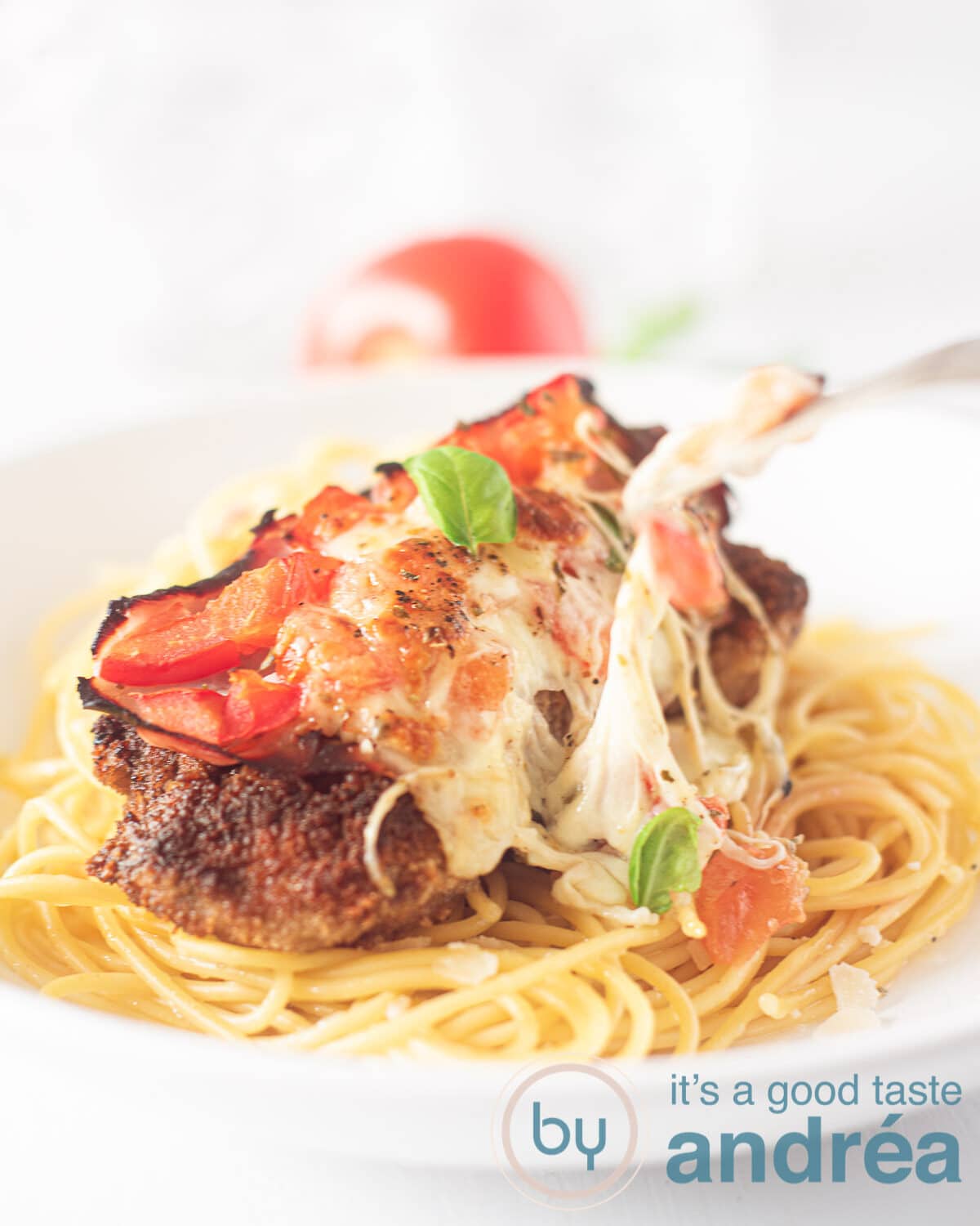 een bord spaghetti met Milanesas napolitana en garnering basilicum