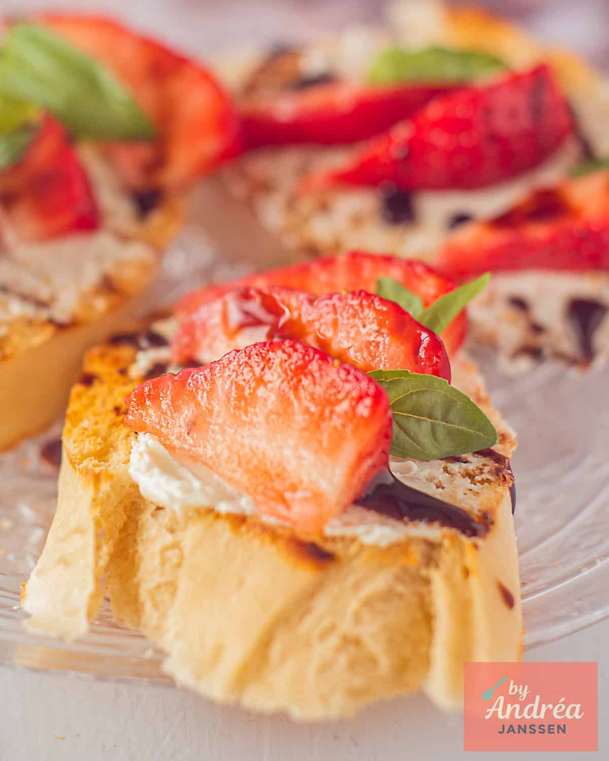 Een glazen bord met drie bruschetta met aardbeien, balsamico en mascarpone.