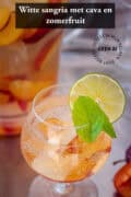 Een glas met sangria met cava en fruit, een tekst bovenin: witte sangria met cava en zomerfruit,