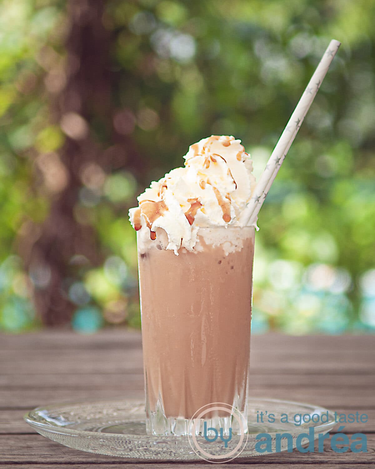 Een glas frappucino met slagroom en karamelsaus in een zomer achtergrond