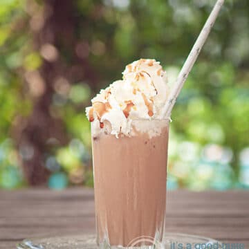 Een glas frappucino met slagroom en karamelsaus in een zomer achtergrond