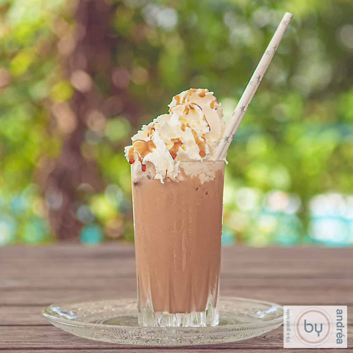 Een vierkante foto van een frappuccino op een houten tafel.