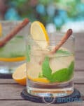 Twee glazen Caipirinha thee cocktail met munt, kaneel en citroen tegen een zomerse achtergrond