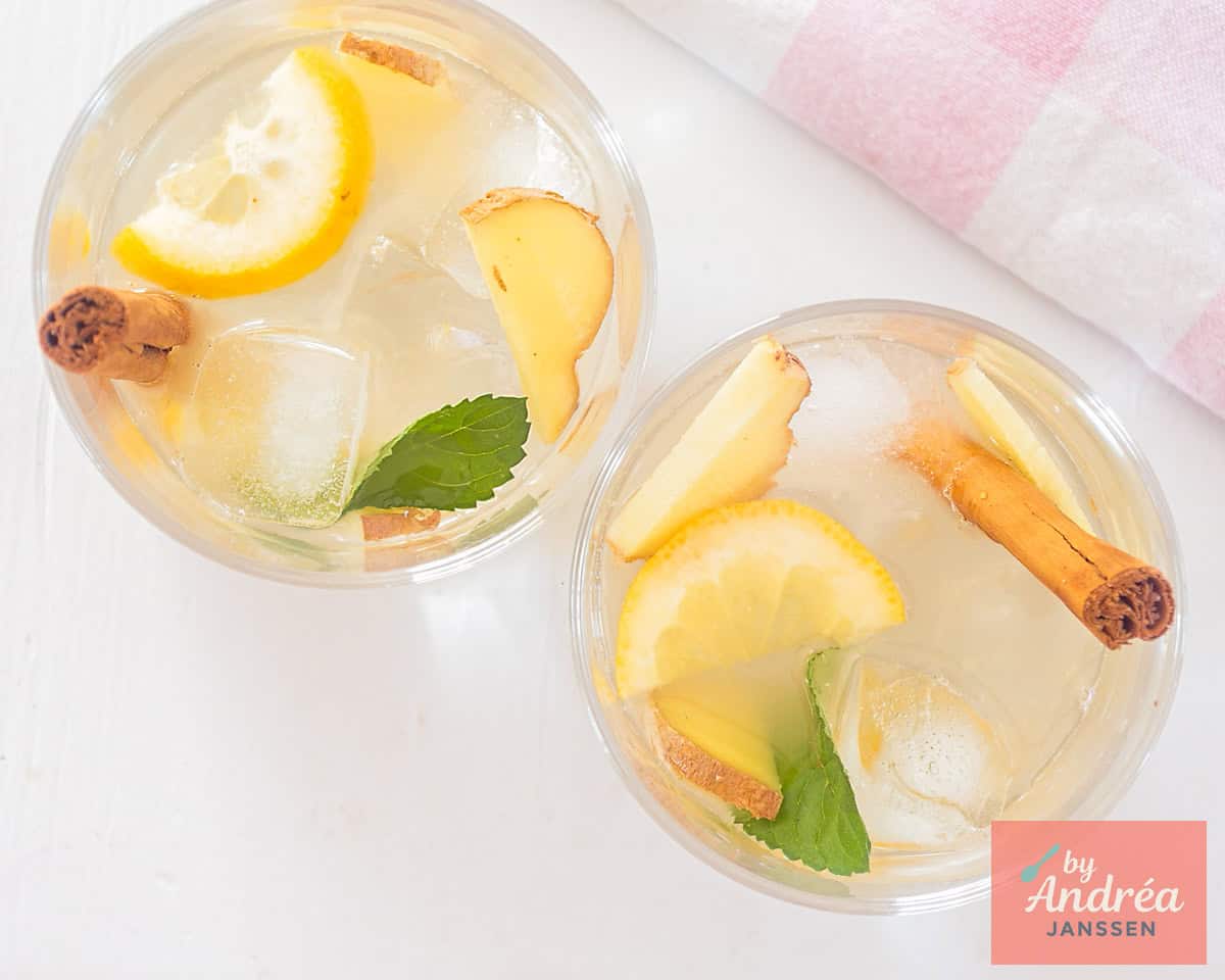 Schenk de caipirinha cocktail in glazen en vul aan met verse munt, citroenschijfjes, ijsklontjes en een stokje kaneel