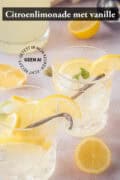 Twee glazen gevuld met vanillelimonade met citroen, schijfjes en vanille stokjes. Een tekst bovenin: citroenlimonade met vanille