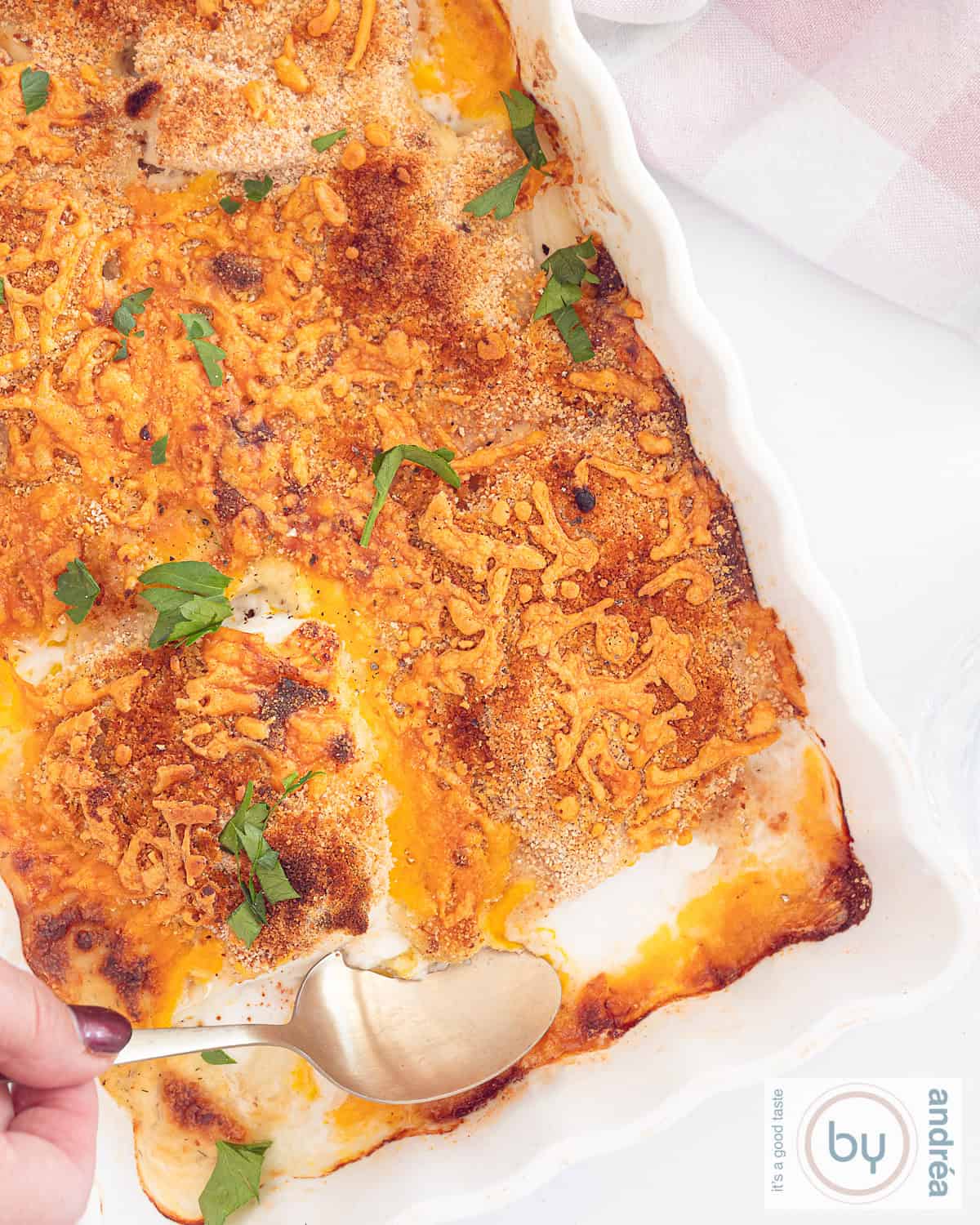 A height picture from above. A white casserole dish filled with cod with a cheesy crust. 