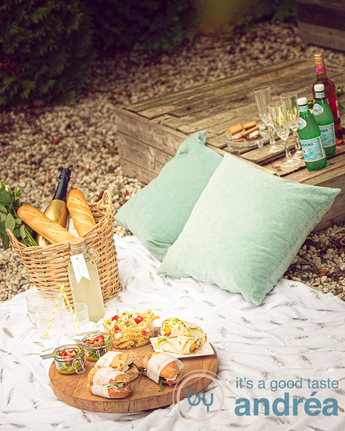 Een kleedje met een uitstalling van picknick gerechten, wijn, water en kusssens. 