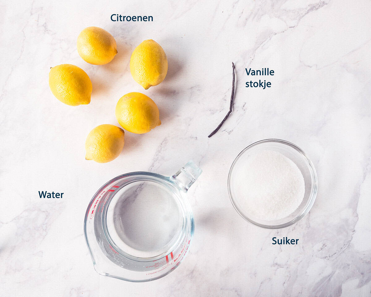 ingredienten Zelfgemaakte citroenlimonade met vanille op een wit marmeren ondergrond met tekstbeschrijving