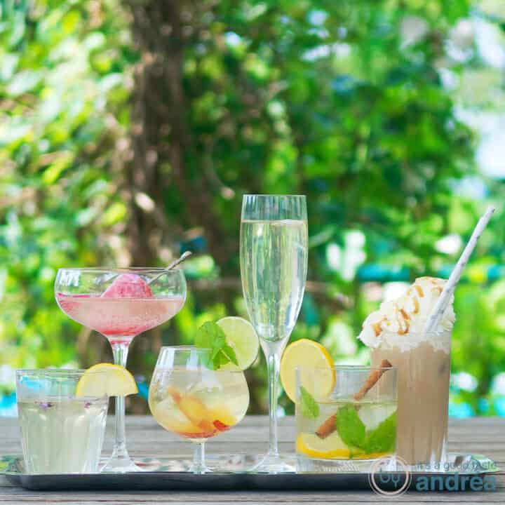 Vierkante foto met zes heerlijke zomerdrankjes op een houten tafel met groen op de achtergrond