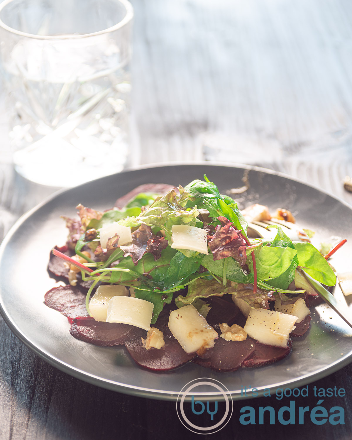 Carpaccio van bieten op een bord, met kaas, rucola, peer en walnoten