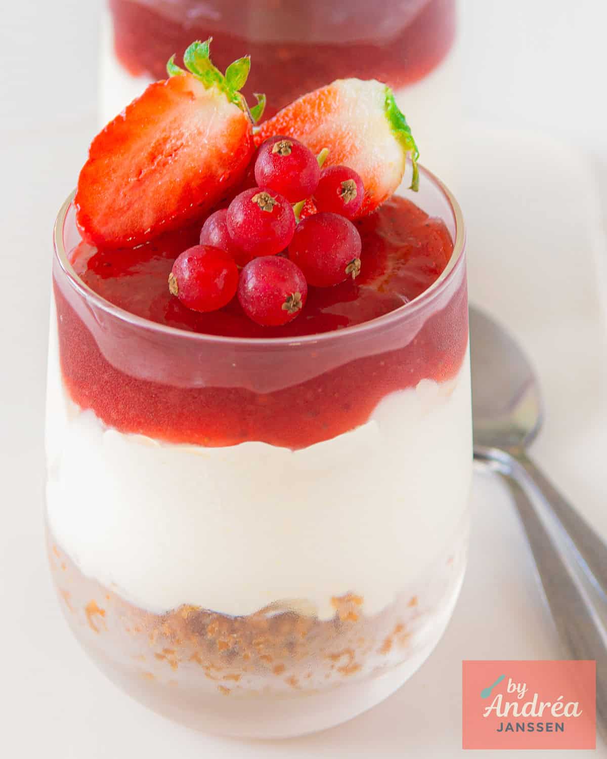 Een glas gevuld met no-bake cheesecake op een witte ondergrond.