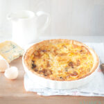 Een tafel met een appel gorgonzola quiche en wat ingrediënten