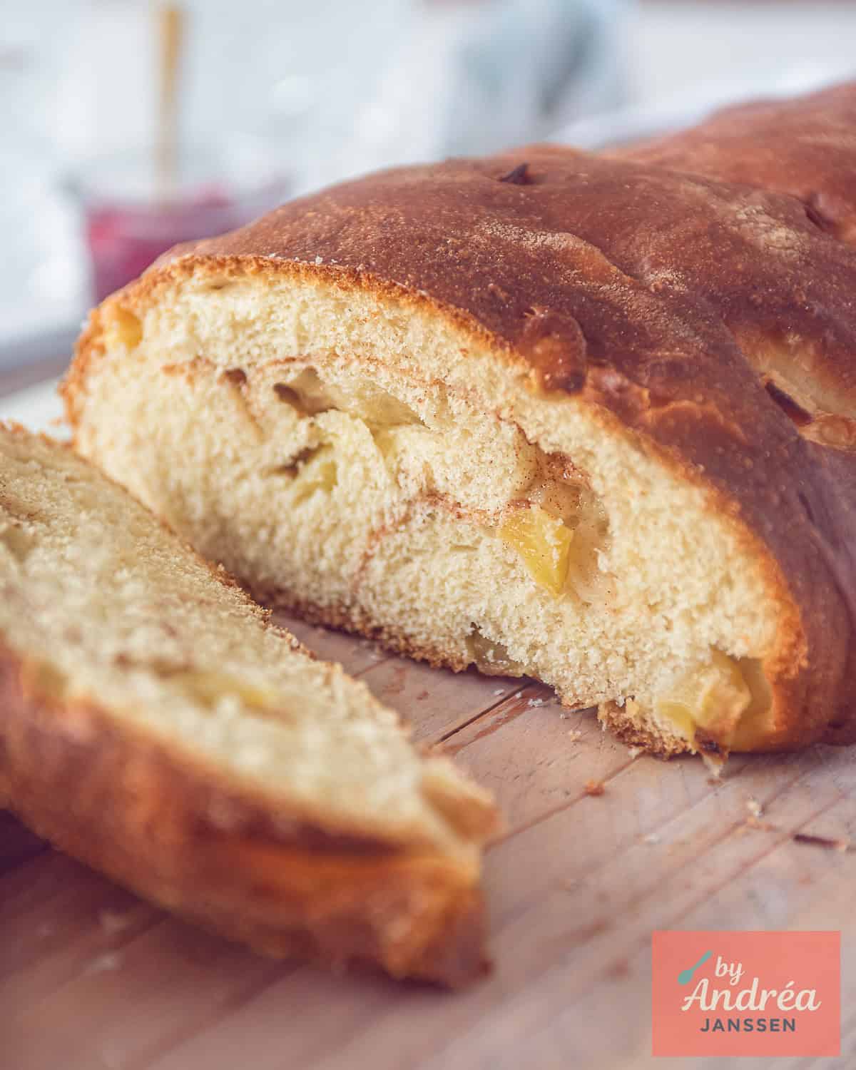 Een appelbrood waar plakken afgesneden zijn op een houten plank