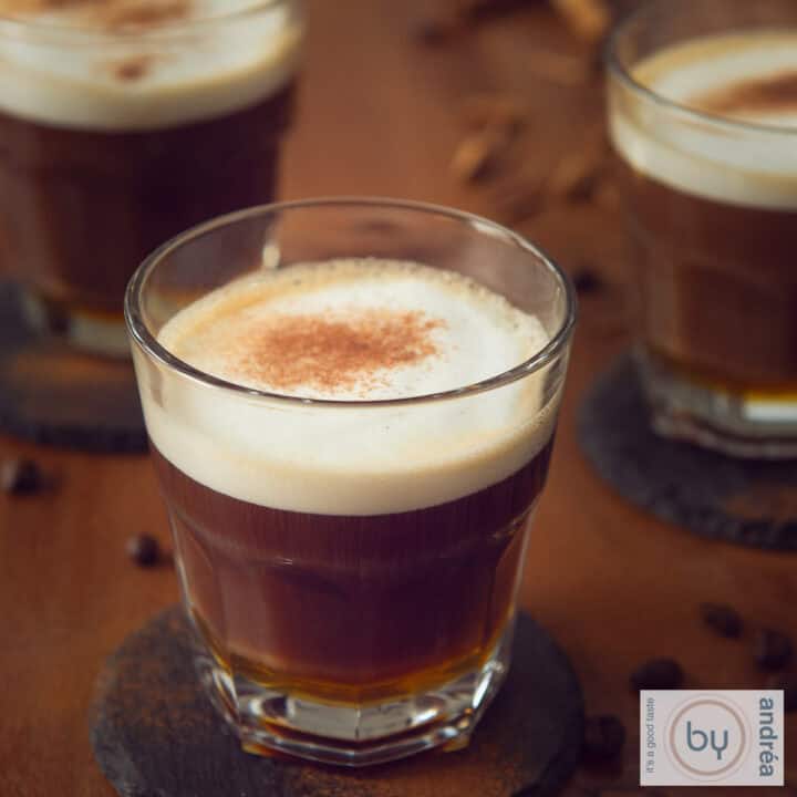 Een vierkante foto met een bruine tafel met drie kopjes met apfelkorn honing café au lait ingeschonken.