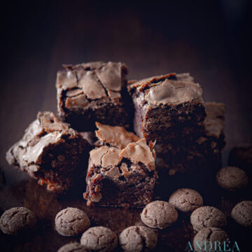 a few cubes of pepernoten brownies between pepernoten on a black backdrop