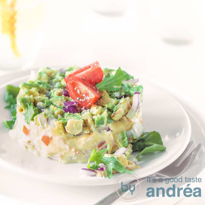 Een vierkante foto met een torentje van gerookte kip avocado salade op een witte ondergrond