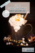 Een zwarte mok op een zwarte ondergrond met marshmallows, gouden steentjes en kaneel. Een toef slagroom zakt naar beneden. Een textoverlay bovenin: luxe chocolademelk met licor 43, drankjes, makkelijk recept, warm drankje