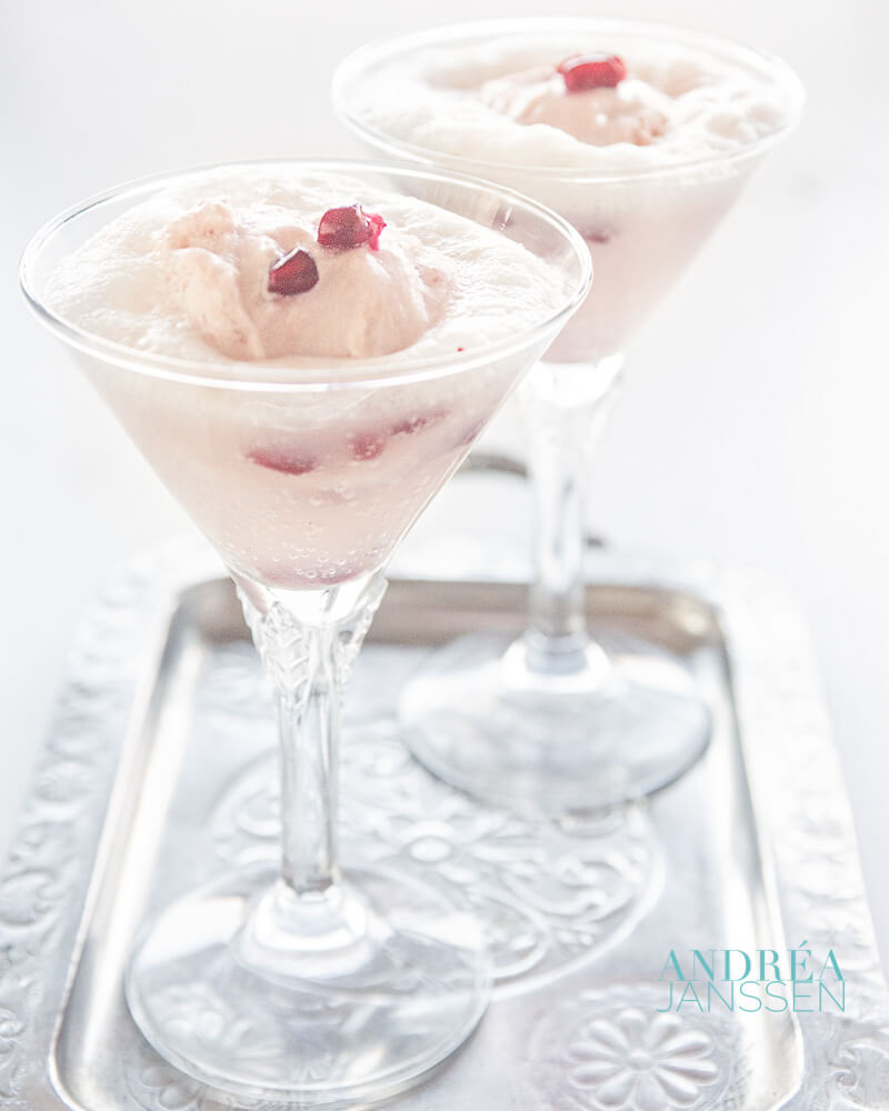 Twee glazen met een spoom van granaatappel yoghurt ijs met prosecco en verse granaatappel pitjes