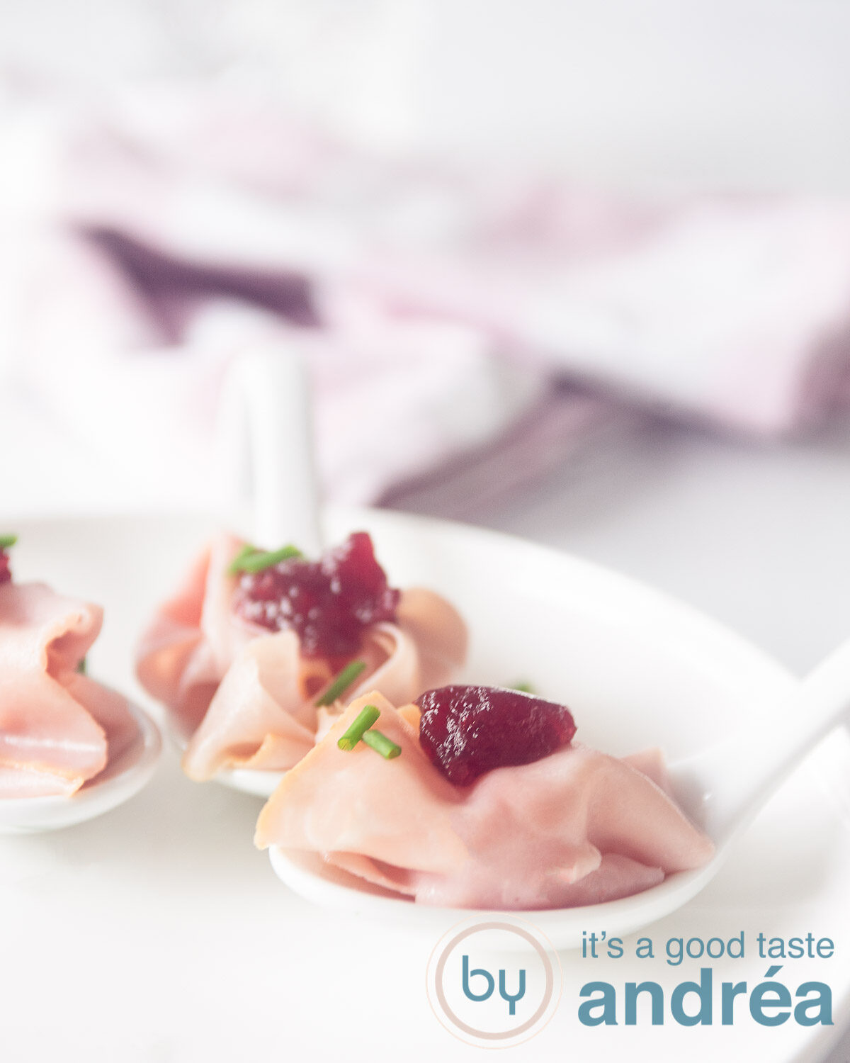 Twee stervormige schaaltjes gevuld met een amuse van flinterdun gesneden ham en cranberry compote