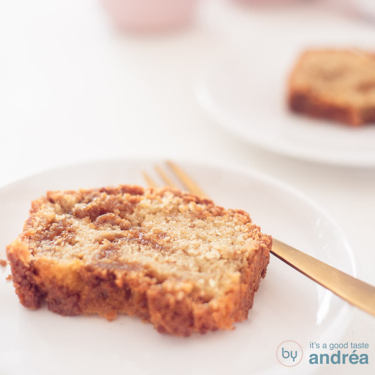 Een vierkante foto met twee bordjes met een plakje stroopwafelcake op een witte ondergrond.