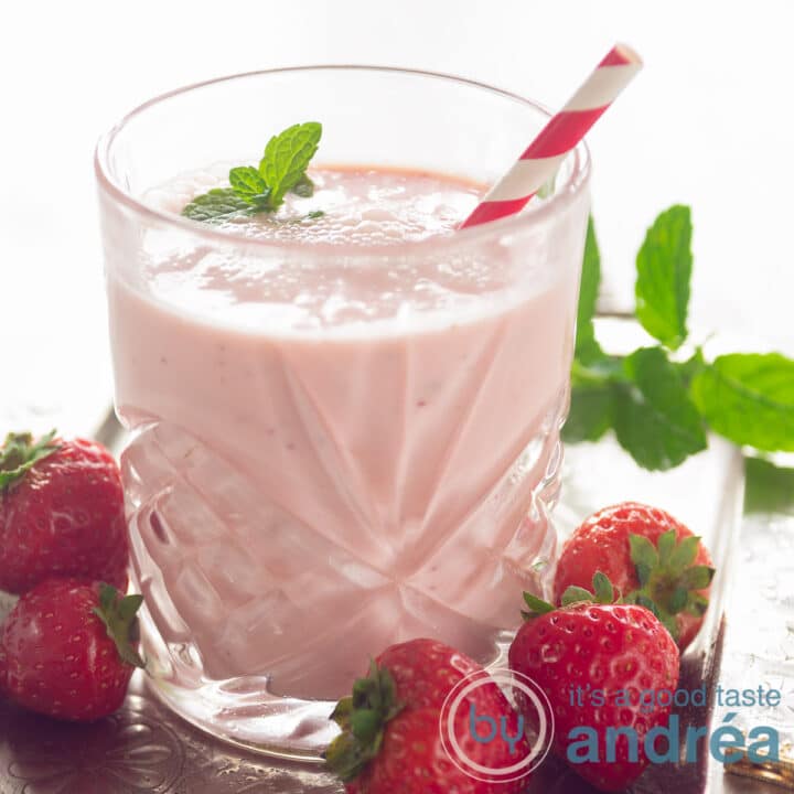 highlight aardbeien yoghurt smoothie vierkante foto met een glas aardbeien smoothie, aardbeien eromheen met munt