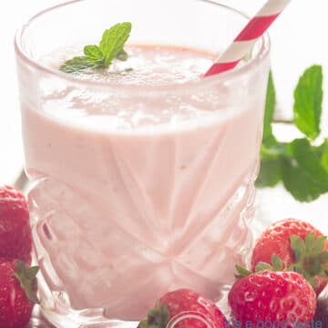 Smoothie Aardbei Yoghurt in een glas met een rietje. Aardeien eromheen.