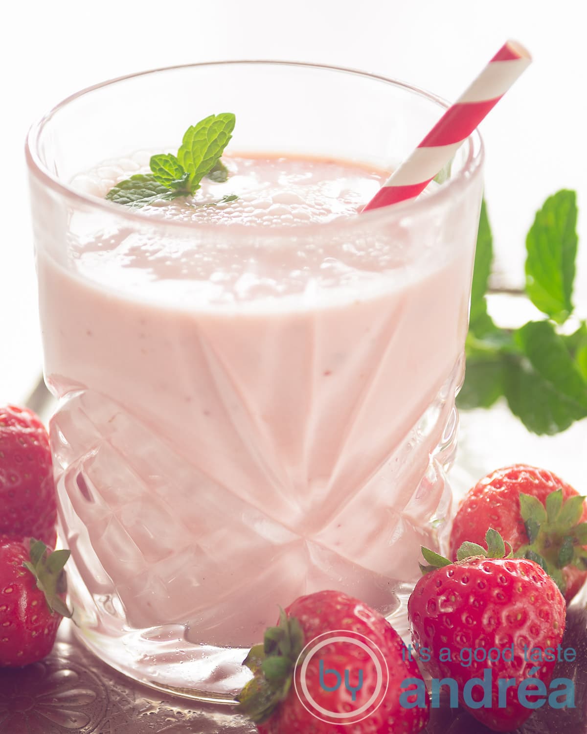 Smoothie Aardbei Yoghurt in een glas met een rietje. Aardeien eromheen.