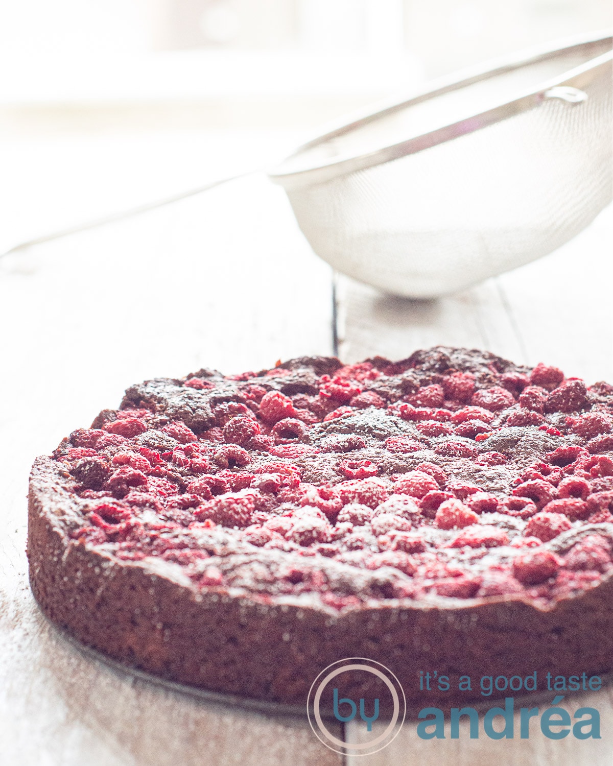 Een witte plank met een frambozen brownie cake bestrooit met poedersuiker