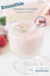 Een glas met daarin een smoothie met aardbeien. Een hand houdt een rietje vast. een text overlay beschrijft de foto