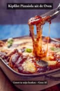 Kipfilet pizzaiola uit de oven met gesmolten mozzarella en tomatensaus, kaastrek close-up in ovenschaal