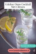 Twee glazen ouzo op een zilveren dienblad. Een tekst bovenin: Griekse Ouzo Cocktail met Citroen