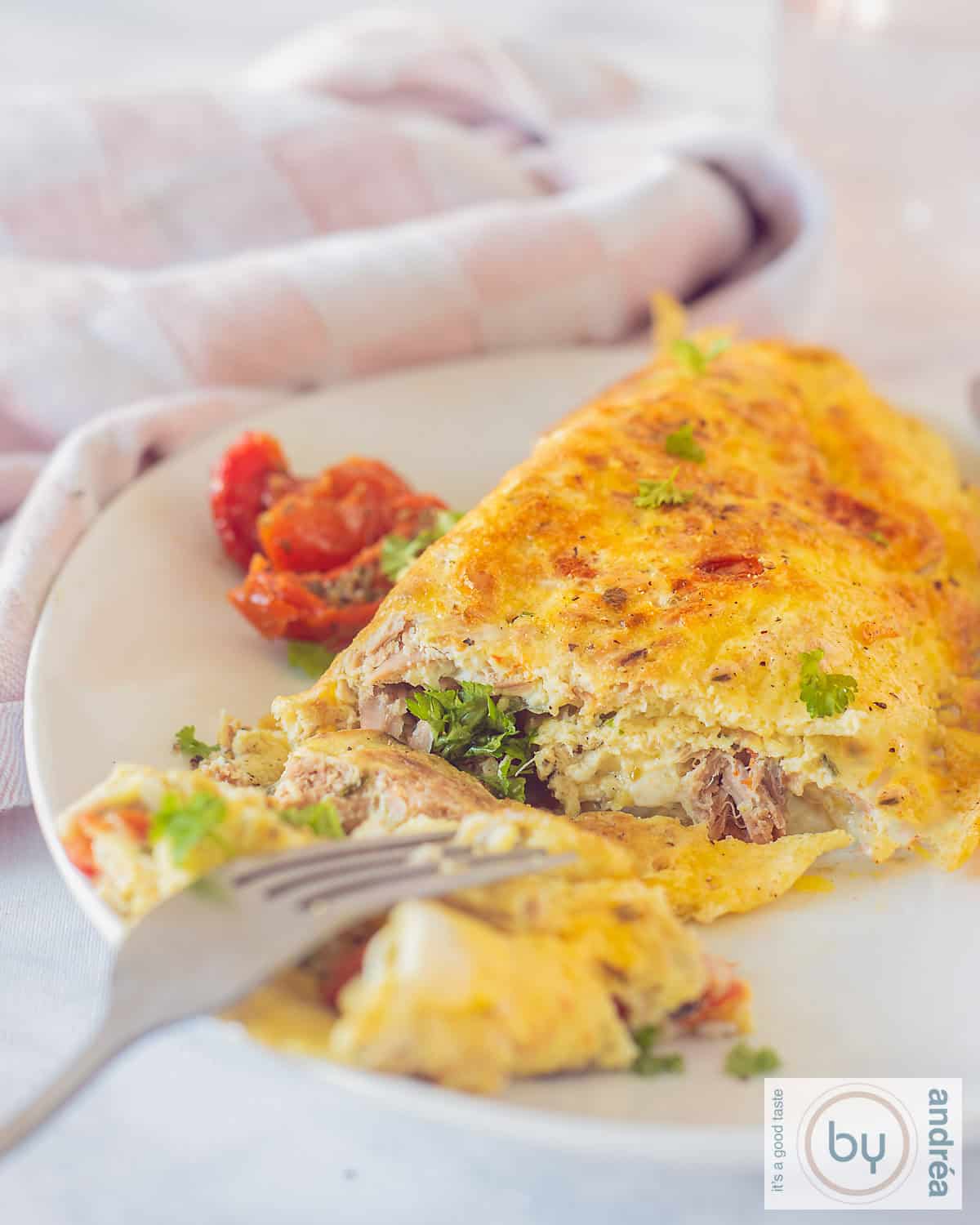 Een opgerolde omelet gevuld met tonijn op een wit bord