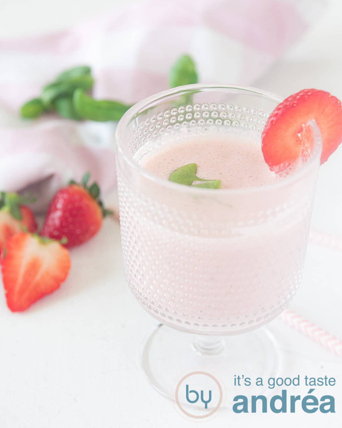 Een glas gevuld met een gezonde aardbeiensmoothie met basilicum en yoghurt