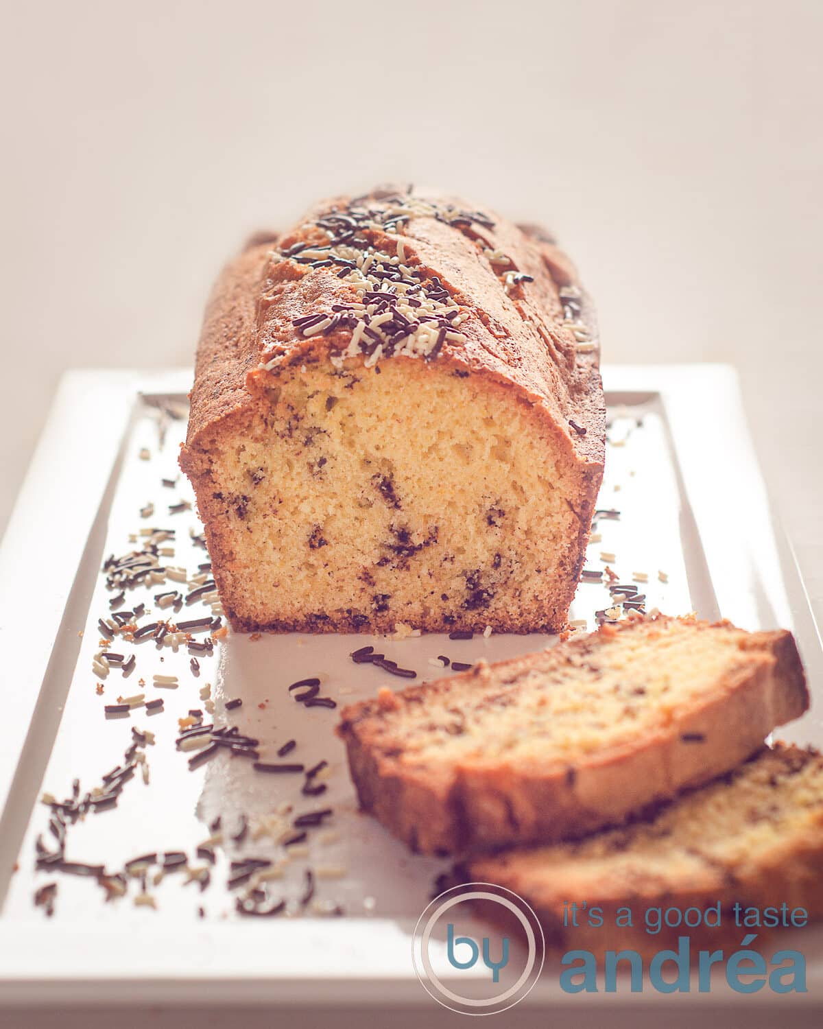 Een halve hagelslag cake op een wit bord, enkele plakjes en hagelslag eromheen gestrooid