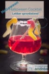 De bovenste helft van een glas gevuld met een bloedrode cocktail. Snoepwormen hangen in het glas. Een text overlay : Halloween Cocktaik, lekker sprankellend, Halloween