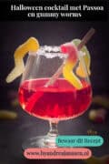 Een glas gevuld met een rode cocktail met wormen. Een tekst bovenin: halloween cocktail met Passoa en gummy worms