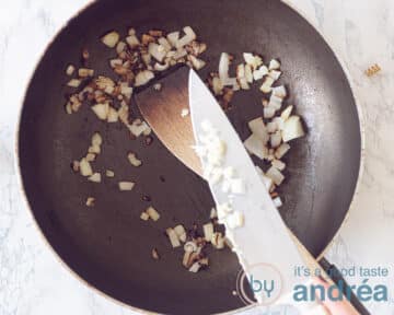 Fruit de ui en knoflook in een pan.