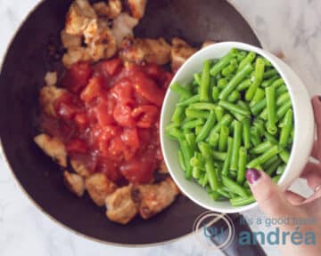 Aan de gebakken kipblokjes worden tomatenblokjes en sperziebonen toegevoegd