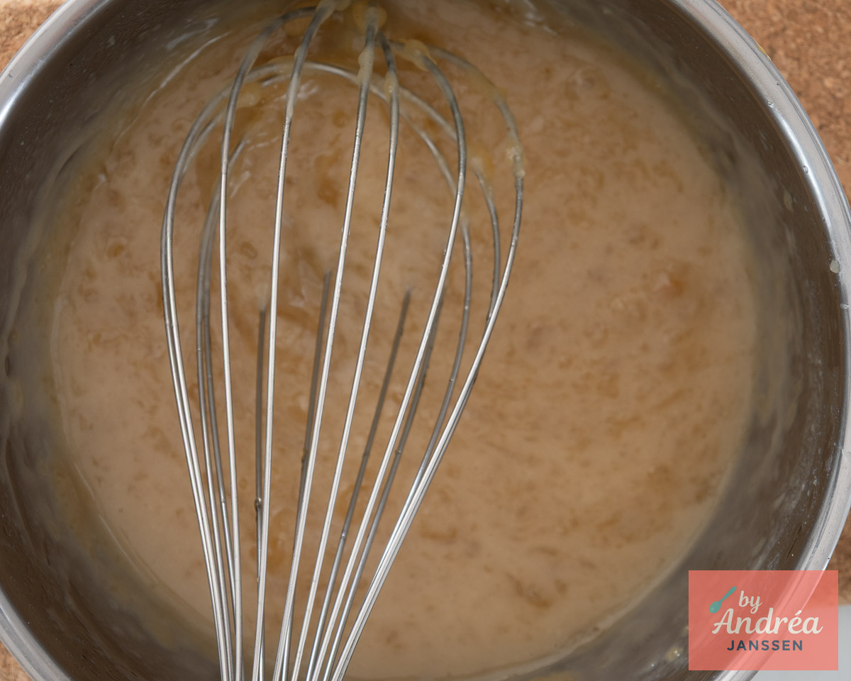 Lichtbruine saus voor de appelvulling in een roestvrijstalen pan met een garde.