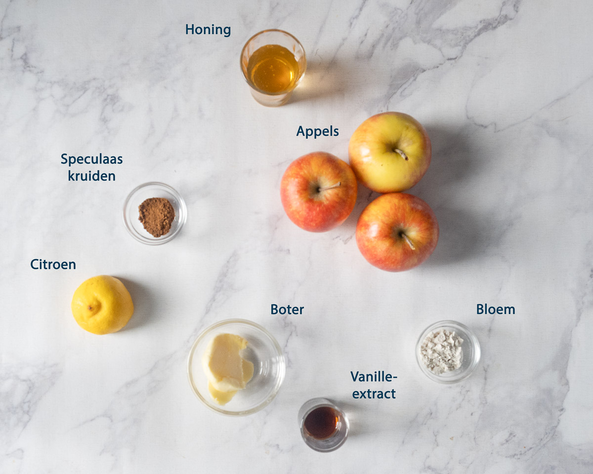 Appels, honing, speculaaskruiden, citroen, boter, bloem en vanille-extract voor de appelvulling, met Nederlandse labels.