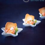 Three amuse bouche star plates filled with smoked salmon, arugula oil and onions on a blue background