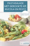 Een deel van een witte schaal met een pesto pastasalade met gerookte kip. Een lepel neemt een hap eruit. Een tekst bovenin: pastasalade met gerookte kip, rucola en pesto, makkelijk recept