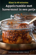 Weckpotje met appelcrumble van havermout en een gouden lepeltje, op een koperen bordje.