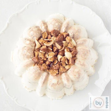Een vierkante foto van bovenaf van pudding met pepernoten op een wit bord op een witte ondergrond