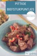 Een blauw schaaltje met biefstukpuntjes met peper en koriander. Een tekst: Pittige biefstukpuntjes, makkelijk recept