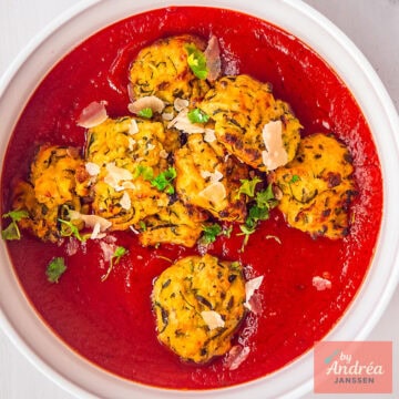 Een vierkante foto van een witte schaal met tomatensaus en gehaktballetjes van courgette, lekker vegetarisch.