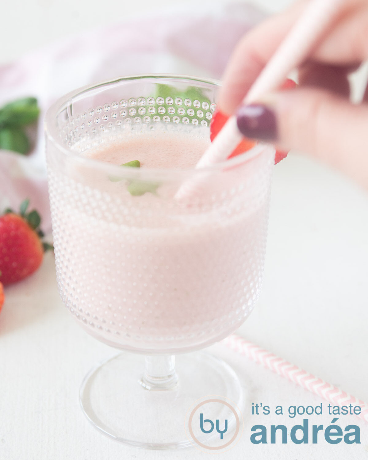 Een flesje met een Aardbeien basilicum yoghurt smoothie en een rood rietje