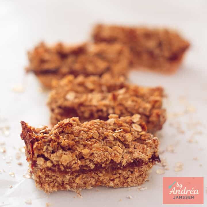 Een vierkante foto met vier havermoutrepen met dadel gevuld achter elkaar gelegd.