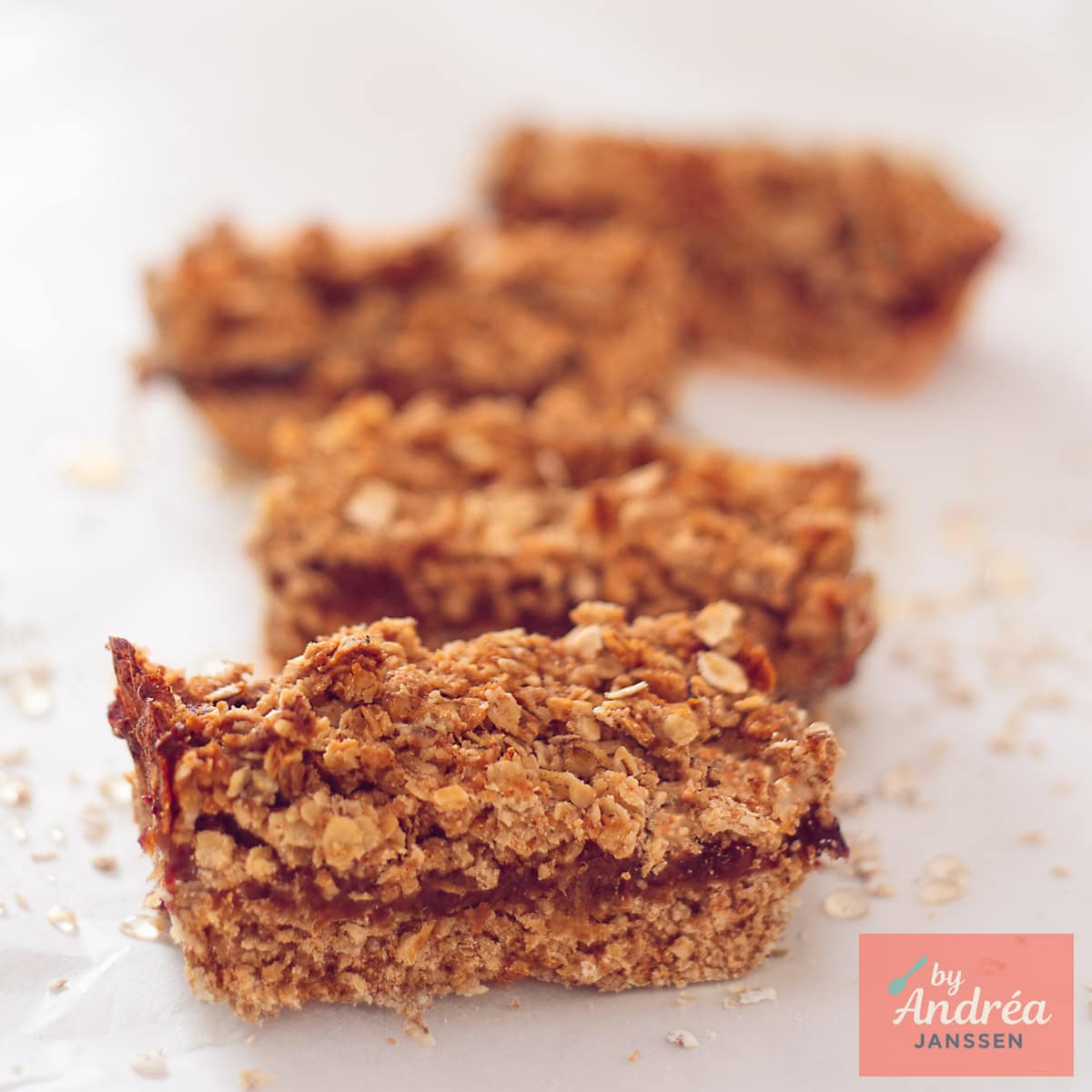 Een vierkante foto met vier havermoutrepen met dadel gevuld achter elkaar gelegd.